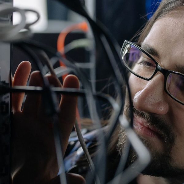 Professional IT specialist handling network cables in a server room.